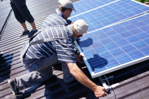 Man installing alternative energy photovoltaic solar panels on roof Melbourne