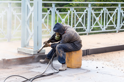 Worker cleaning metals using sandblasting in Melbourne